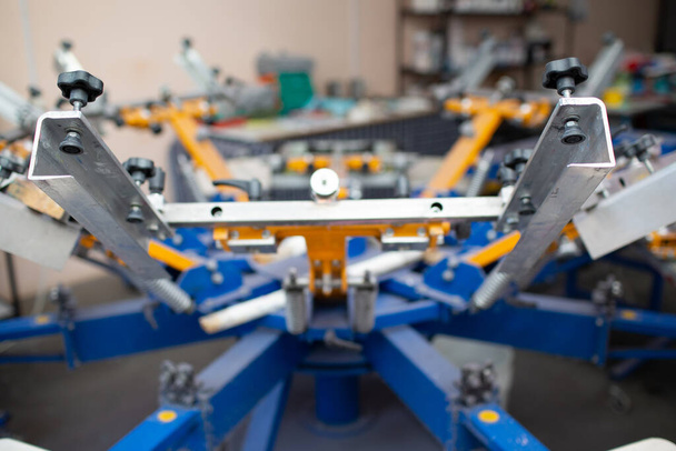 Διαδικασία εκτύπωσης μεταξοτυπίας Serigraphy στο εργοστάσιο ρούχων. Carousel Frame, χρώματα squeegee και πλαστισόλης - Φωτογραφία, εικόνα