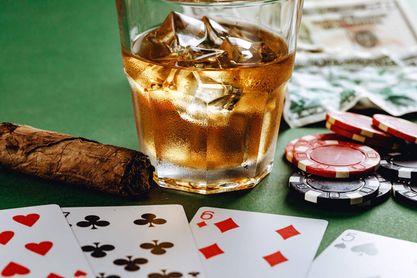 Glass of whiskey, cigar, playing cards and chips on green background - Fotografie, Obrázek
