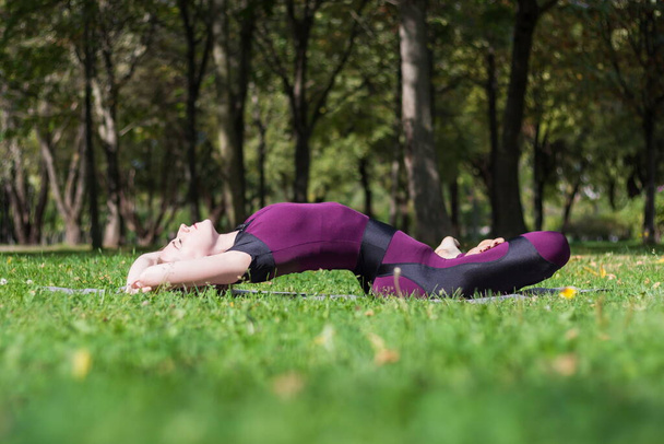 стройная молодая привлекательная блондинка практикует йогу позирует в летнем солнечном парке - Фото, изображение