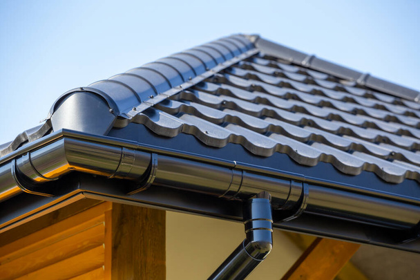 Corner of the new modern house with roof, gutter and wooden shutter under blue sky - 写真・画像