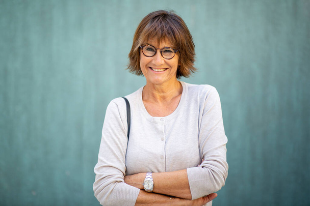 Портрет літньої жінки, яка посміхається окулярами і схрещеними руками
 - Фото, зображення