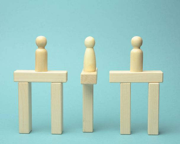 little wooden men stand on the destroyed bridge on different sides on a blue background negotiator between them. The concept of finding a compromise, constructive dialogue, business opponents - Photo, Image