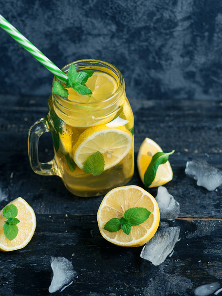 Vaso di vetro con limonata estiva. Bere con limone e menta su un tavolo di legno. Mojito fatto in casa - Foto, immagini