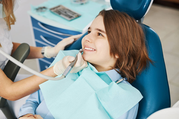 Emocionado adolescente recibiendo tratamiento de cuidado dental del dentista - Foto, Imagen