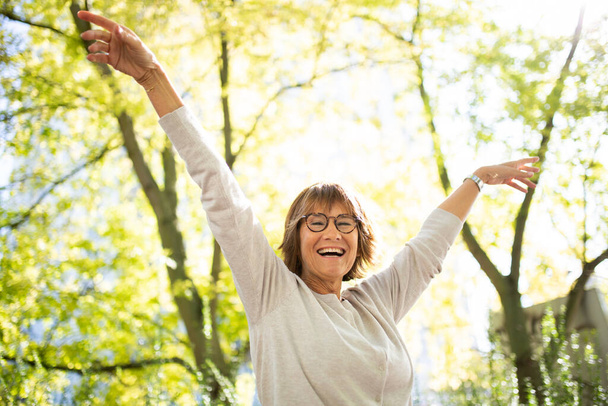 Портрет счастливая пожилая женщина с вытянутыми руками в природе - Фото, изображение