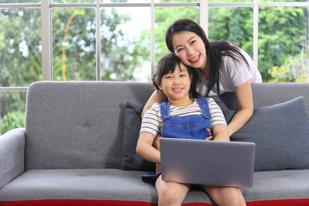 Madre asiática enseñando a su hija a aprender de la clase en línea utilizando el ordenador portátil para la educación en el hogar y el concepto de educación - Foto, imagen
