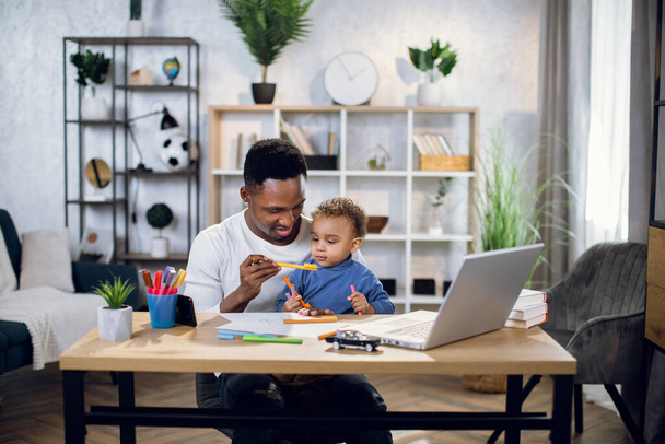 Afro american man working on laptop and playing with son - Foto, immagini