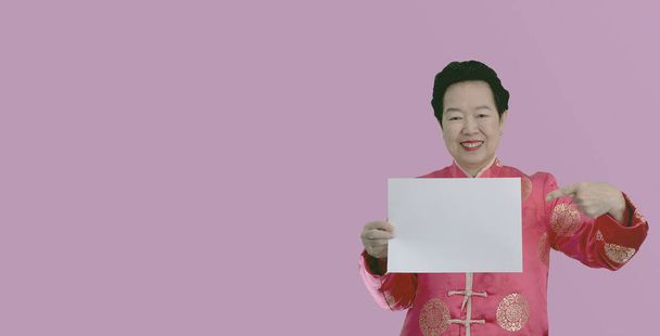 Asian seniior elder woman in Chinese new year red costume holding white board space for happy advertising - Foto, Bild