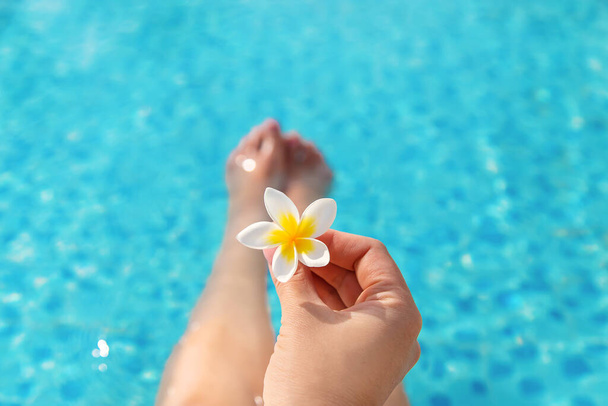 Κορίτσι κοντά στην πισίνα με ένα λουλούδι. Επιλεκτική εστίαση. φύση. - Φωτογραφία, εικόνα