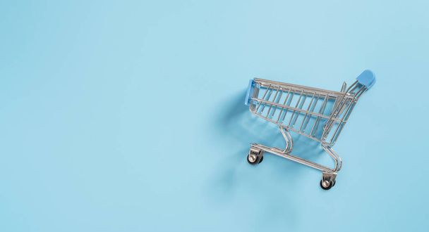 Small shopping cart trolley on blue background for online shopping and e-commerce concept. - Foto, Imagen