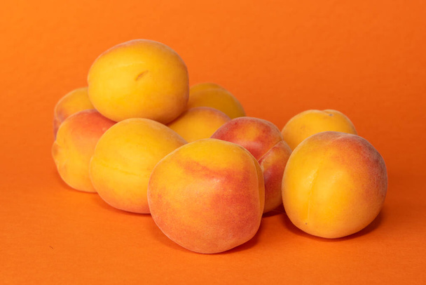 Pile of small, fresh, ripe, juicy, peaches on a colourful background, stock picture. - Fotó, kép
