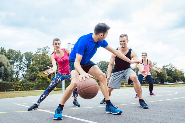 Basketball players playing at outdoors court - Photo, Image