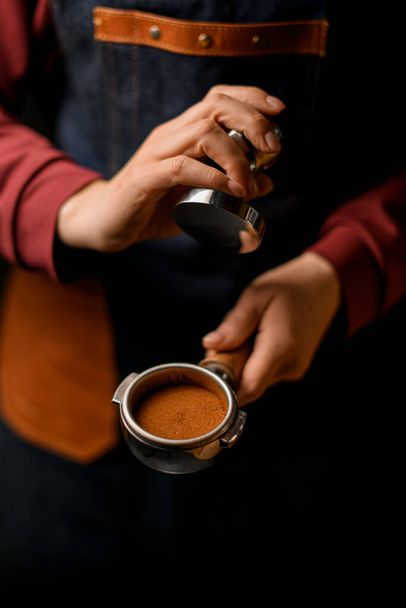 Woman barista holds in her hand portafilter with pressed ground coffee inside it. - Foto, imagen