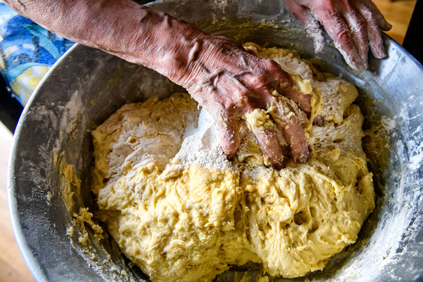 Hands of an elderly woman who making a large portion dough for baking at home. High quality photo - Foto, Bild
