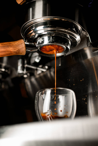 Coffee machine pouring espresso in double wall glass from bottomless naked portafilter. - Foto, Imagem