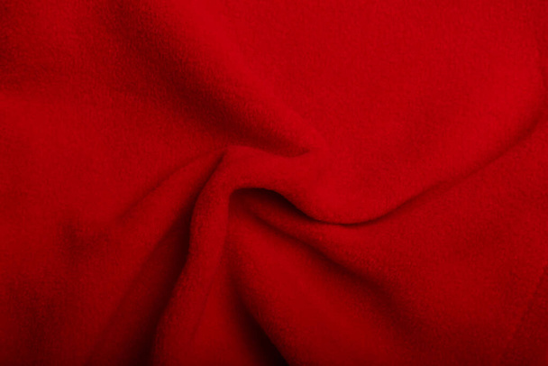 Textura červené rouno vrásčité tkaniny, pozadí nebo pozadí. Oděvy, šití, promoce, galanterie. Kopírovat prostor. - Fotografie, Obrázek