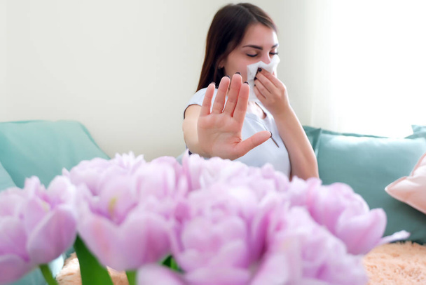 Stop the flowers. young woman sneezes from flower allergy. Pollen allergy - 写真・画像