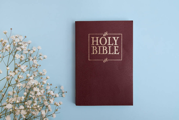 Top view of holy bible on round with flowers on blue background - Photo, Image