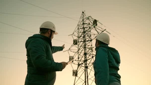 Teamwork and engineers, partners shaking hands, good work. Business concept. Woman and man work together. Power workers in protective white helmets are checking power line online using computer tablet - Footage, Video