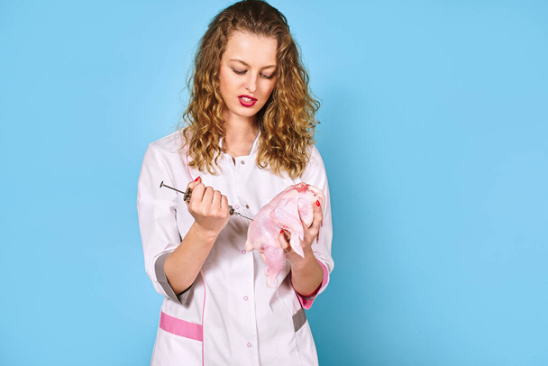 girl doctor makes an injection of chicken with large syringe. concept - Foto, Bild