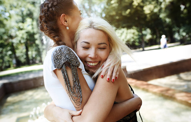 Zwei Freundinnen umarmen sich im öffentlichen Park - Foto, Bild