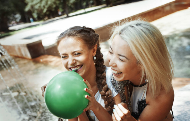 Two girlfriends having fun and blowing balloons - Foto, Imagen