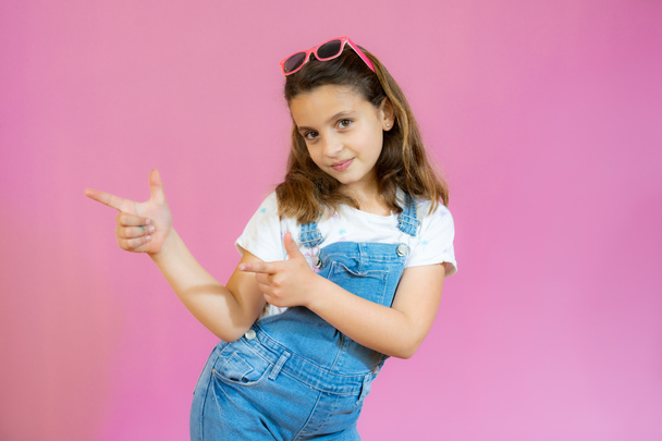 Beautiful child girl wearing casual clothes smiling and looking at the camera pointing with two hands and fingers to the side. - Foto, Bild