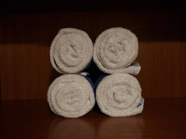 Stapel von vier sauberen Handtuchrollen auf Holzregalen - Foto, Bild