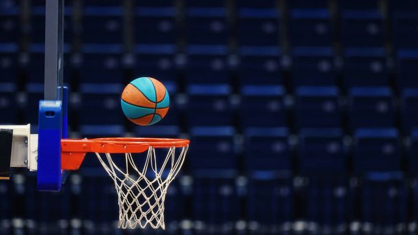 Canestro da basket con una palla sullo sfondo dei posti vuoti dell'arena sportiva - Foto, immagini