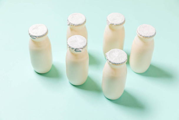 Małe butelki z probiotykami i prebiotykami napój mleczny na niebieskim tle. Produkcja z użyciem biologicznie aktywnych dodatków. Fermentacja i dieta zdrowej żywności. Biojogurt z użytecznymi mikroorganizmami - Zdjęcie, obraz