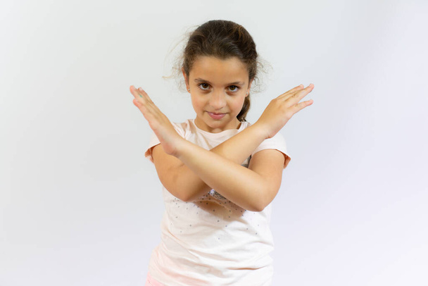 девочка в повседневной футболке, стоящей на изолированном белом фоне Отказ выражение лица скрещивание рук делает негативный знак - Фото, изображение