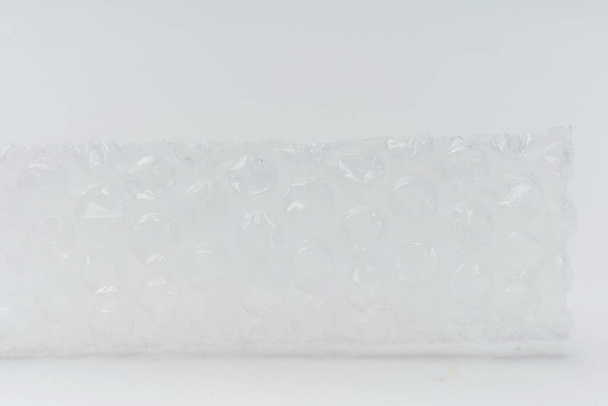 Envoltura de burbuja sobre un fondo blanco de cerca. Película para embalaje de productos y objetos frágiles - Foto, Imagen