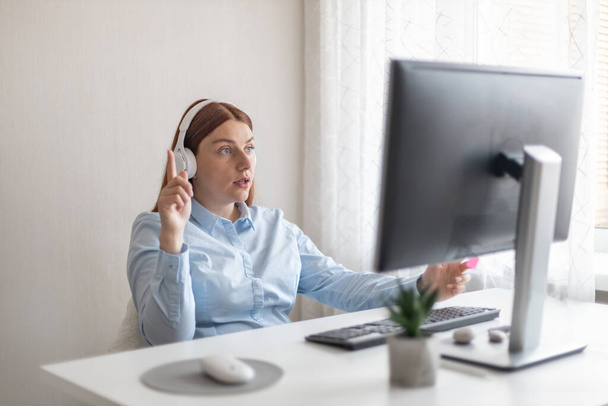 Ofiste kulaklıkla dijital bir bilgisayarda çalışan yaratıcı beyaz bir iş kadını.. - Fotoğraf, Görsel
