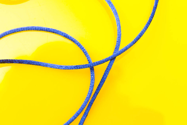 Corda azul fina no fundo amarelo, rosca bagunçada fora do carretel sem ordem, confusão de corda. - Foto, Imagem