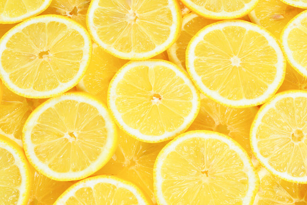 Кусочки свежих сочных желтых лимонов. Текстура фона, рисунок. - Фото, изображение