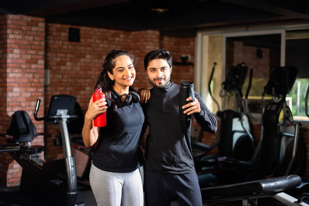 Indiai ázsiai fiatal pár edz az edzőteremben. Vonzó nő és jóképű fitt férfi edzés modern tornaterem - egészség és fitness koncepció - Fotó, kép