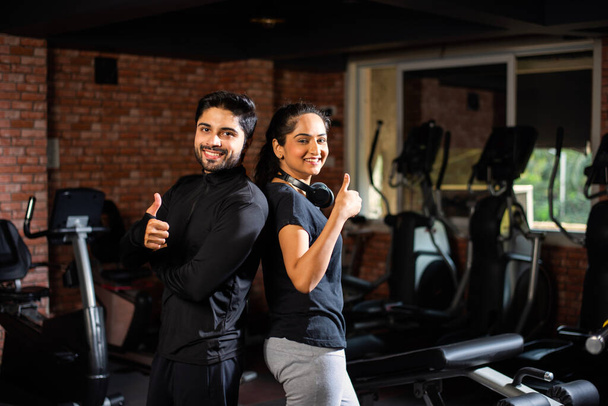 Indisch asiatisch jung pärchen ist workout im die fitnessstudio. Attraktive Frau und gut aussehender, fitter Mann trainieren im modernen Fitnessstudio - Gesundheits- und Fitnesskonzept - Foto, Bild