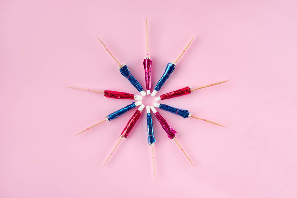 Decorative cocktail umbrellas in form of a circle on summertime pink background - Photo, Image
