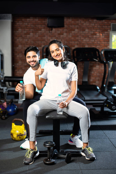 Młoda Hinduska para ćwiczy na siłowni. Atrakcyjna kobieta i przystojny sprawny mężczyzna trenują w nowoczesnej siłowni - koncepcja zdrowia i fitness - Zdjęcie, obraz