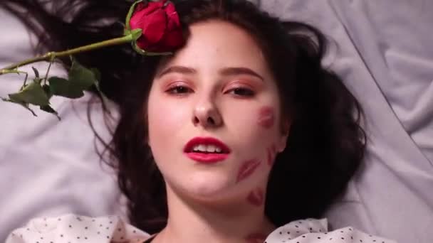 sexy mujer morena con besos, marcas de lápiz labial en la cara y el cuello, con rosa roja. novia, cita, relashionship - Metraje, vídeo