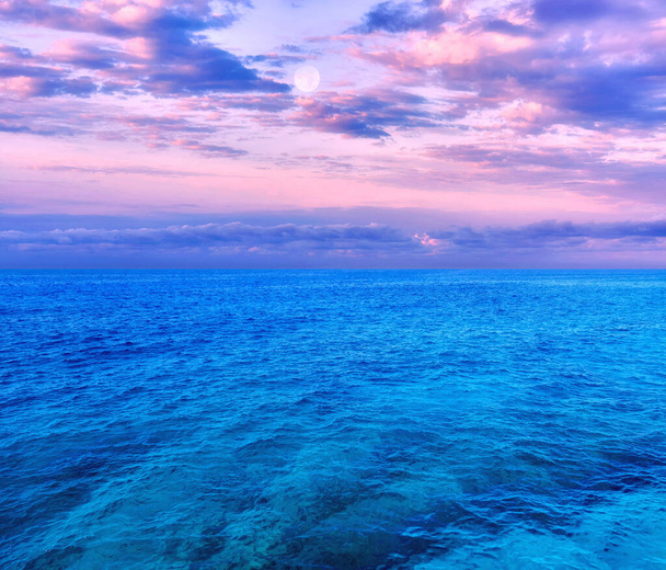 Рожевий захід з повним місяцем і драматичні хмари над Середземним морем влітку. - Фото, зображення
