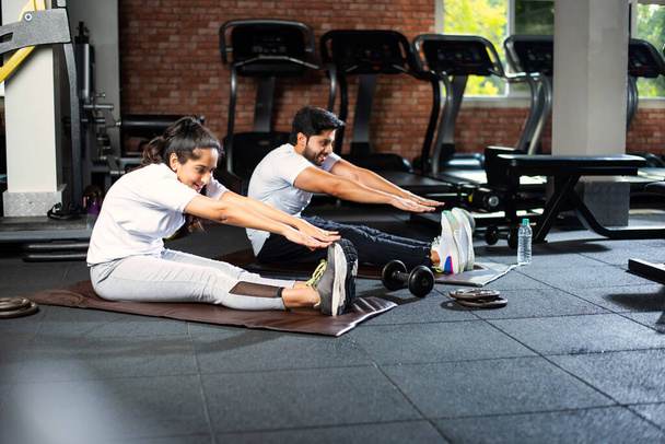 Sportif Hintli genç çift, serinlemek ve esnekliği arttırmak için spor sonrası egzersiz yapıyor. - Fotoğraf, Görsel