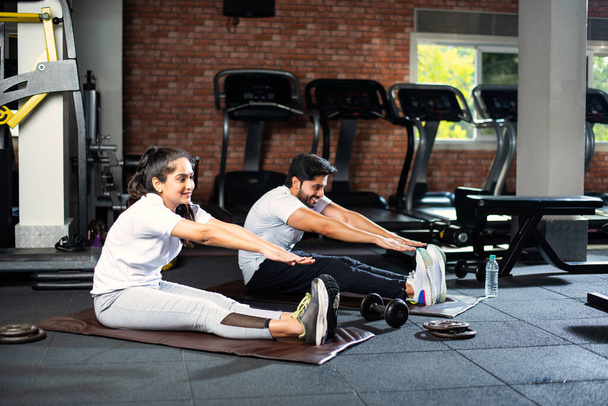sportif indien asiatique jeune couple étirement dans gymnase post exercice pour refroidissement vers le bas, améliorer la flexibilité - Photo, image