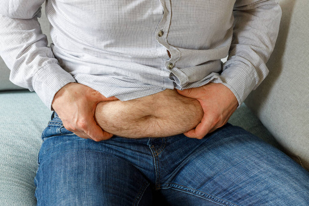 Homem com excesso de peso apertando sua barriga exposta com as duas mãos, conceito de obesidade e problemas de saúde relacionados ao colesterol  - Foto, Imagem