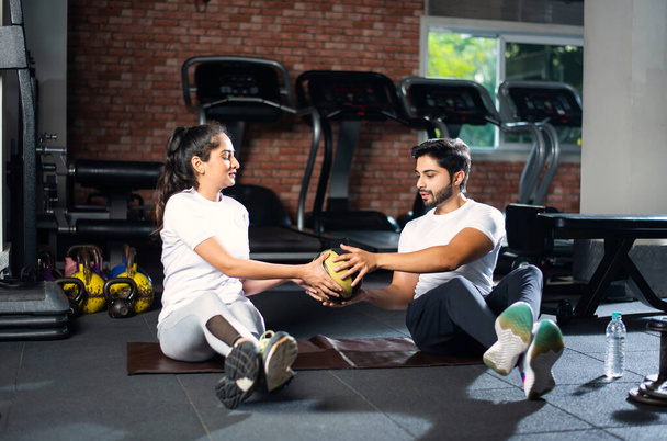 Indian asian young Fit couple doing exercises with passing the ball to each other on yoga mat on floor. - Photo, Image
