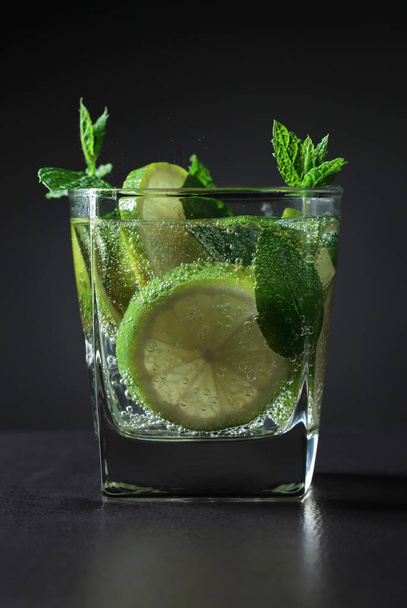 Cold carbonated drink with lime and mint on a black table. - Fotografie, Obrázek