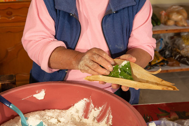 Femme autochtone préparant des tamales au masa, farcies de légumes, recouvertes d'une feuille de maïs, nourriture traditionnelle mexicaine. - Photo, image