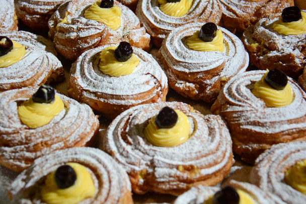 typical Italian dessert for Father's Day and St. Joseph's Day: zeppola filled with custard and a black cherry - Photo, Image
