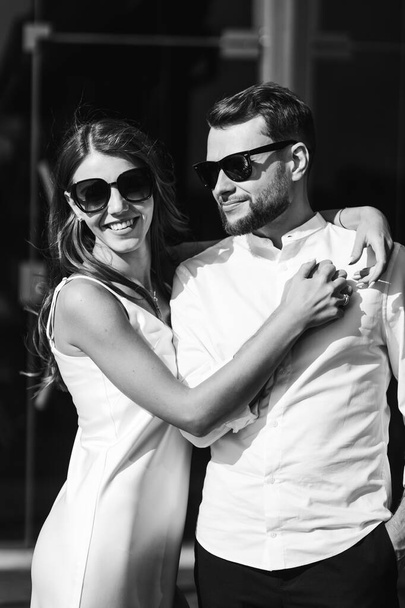 Recién casados sonrientes en el fondo de una pared espejada abrazo tiernamente. Foto en blanco y negro. - Foto, imagen
