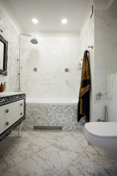 Modern bathroom with marble tiles, luxurius wardrobe and white toilet - Фото, зображення
